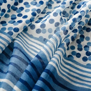 Detailed macro view of blue and white polka dot scarf fabric with soft fringes