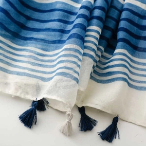 Detail of blue and white striped scarf with handcrafted tassels and woven texture