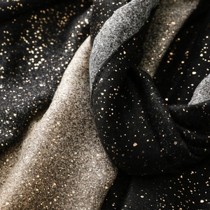 Macro detail of cotton-linen scarf featuring gold foil starburst patterns and gradient textures