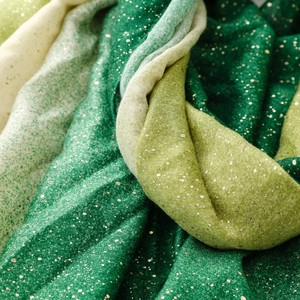 Detail of gradient green scarf with gold foil accents and soft textured fabric draping
