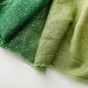 Detail of green cotton linen scarf featuring gold foil speckles and fringe edges