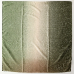 Detail of gradient green scarf with silver star-like foil print and frayed edges
