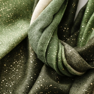 Macro shot of dark green cotton linen scarf with elegant gold foil speckled texture