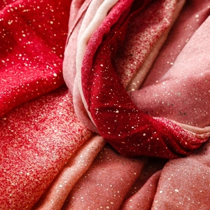 Macro detail of red gradient scarf with golden sequins and soft woven texture