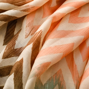 Detailed macro view of the woven linen texture and orange wave print on this soft scarf