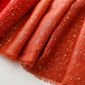 Detail of red cotton linen scarf with gold foil accents and soft fringed edges