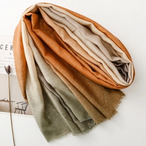 Close-up of a gradient cotton linen scarf with gold foil details and frayed edges