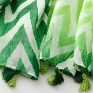 Detail of green wave pattern scarf with hand-knotted bicolor tassels and cotton linen texture