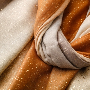 Detail of warm cotton linen blend scarf with metallic gold foil accents and gradient stripes