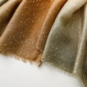 Detailed texture of cotton linen scarf with gold foil accents and soft fringe edges
