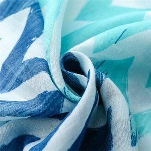 Macro detail of scarf showing blue abstract wave pattern and linen-like texture