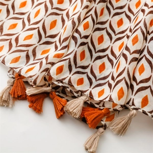 Detail of bohemian scarf with orange geometric diamond patterns and fringe tassels
