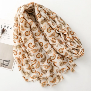 Détail du motif paisley et des bords effilochés sur une écharpe beige en coton et lin