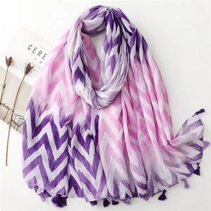 Detailed flat lay of purple and pink wave pattern scarf with elegant fringe and magazine