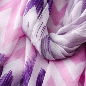 Macro view of light linen scarf featuring purple zigzag patterns and woven texture detail