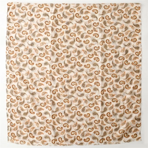 Détail d'une écharpe beige en coton avec motifs paisley orange et bords effilochés doux