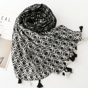 Detail of black and white geometric scarf with tassels on minimalist background