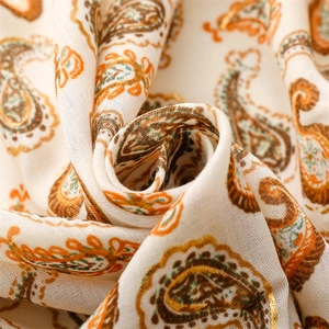 Gros plan du foulard à motif paisley avec détails orange et vert sur tissu effet lin