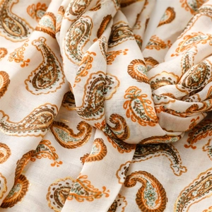 Détail de motifs paisley dorés sur un châle en coton et lin de couleur crème doux