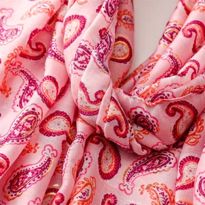 Détail d'une écharpe en coton et lin rose avec motif cachemire doré et bords effilochés