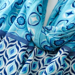 Detailed close-up of blue star and moon geometric patterns on soft linen scarf fabric