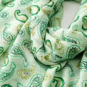 Détail macro d'une écharpe cachemire vert menthe avec motifs dorés métallisés
