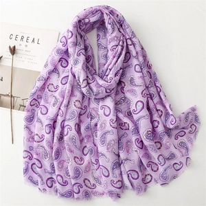 Détail d'une écharpe violette à motif cachemire avec bords effilochés et dorure sur surface