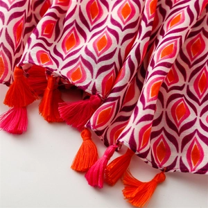 Detailed view of colorful geometric diamond pattern scarf with vibrant orange fringe tassels