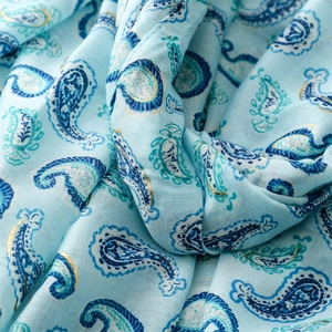 Gros plan détaillé de l'écharpe bleu clair à motifs paisley dorés avec bords effilochés