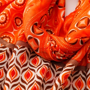 Detailed view of orange cotton linen scarf with geometric patterns and tassel fringe