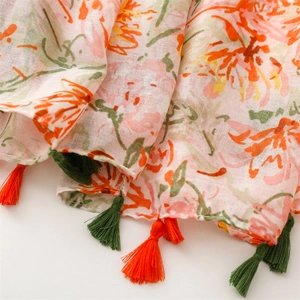 Detailed close-up of summer floral print scarf with vibrant green and orange tassels
