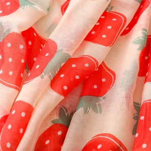 Macro detail of soft cotton-linen fabric with vibrant red strawberry pattern and fine texture