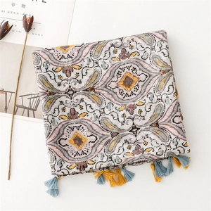 Macro detail of bohemian scarf featuring intricate floral patterns and colorful tassels