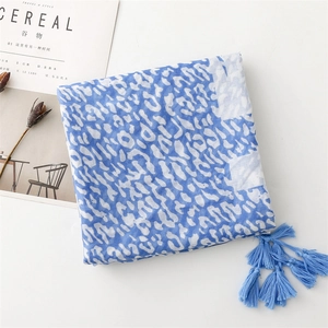 Flat lay of a leopard print scarf with blue tassels next to a minimalist magazine