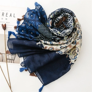 Detail of blue paisley and geometric print scarf with tassels on white background