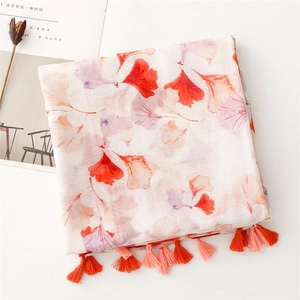 Detail view of voile shawl featuring orange ginkgo leaf prints and tassel trim fringe