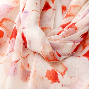 Macro detail of breathable voile scarf with orange maple leaf print and soft fabric texture