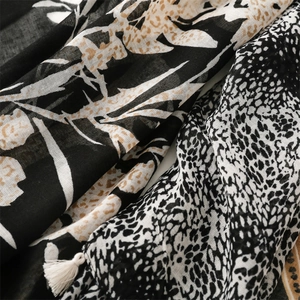 Close-up of leopard floral scarf fabric showing mixed patterns and white silk tassel detail