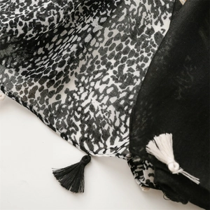 Detail of leopard print and solid black fabric patchwork scarf with handmade tassels