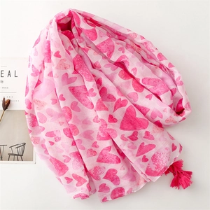 Detail of pink scarf with heart prints and tassels on light cotton linen fabric