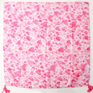 Detailed view of pink heart print scarf with decorative tassels and lightweight fabric