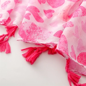 Close-up of pink heart print scarf featuring vibrant magenta tassels and soft texture