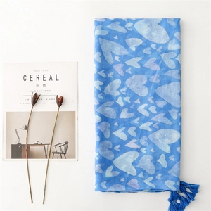 Detailed view of blue cotton linen scarf with white heart patterns and fringe edges