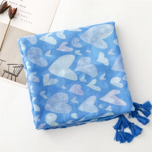 Detail of light blue cotton scarf featuring heart patterns and blue fringe tassels