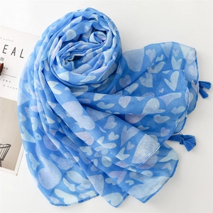 Close-up of light blue cotton linen scarf featuring white heart prints and fringe tassels