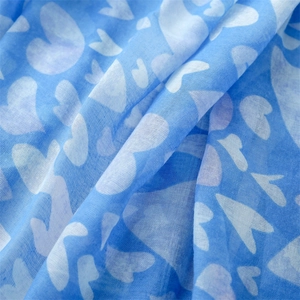 Detail of light blue cotton-linen scarf fabric with white heart patterns and soft texture