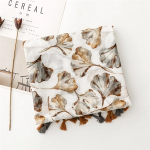 Detail of artistic ginkgo leaf print scarf with elegant grey and brown tassels edge