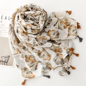 Detailed shot of white voile scarf featuring ginkgo leaf prints and two-tone tassels