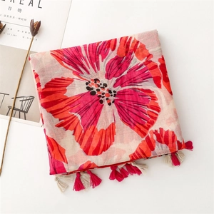 Close-up of red floral print scarf with soft tassels and delicate woven fabric texture