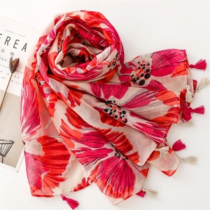 Detail of red floral scarf with fringe tassels and soft fabric texture on white background